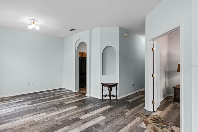 empty room with dark wood-type flooring and a textured ceiling