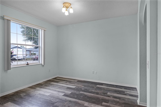 unfurnished room featuring dark wood-type flooring and a textured ceiling