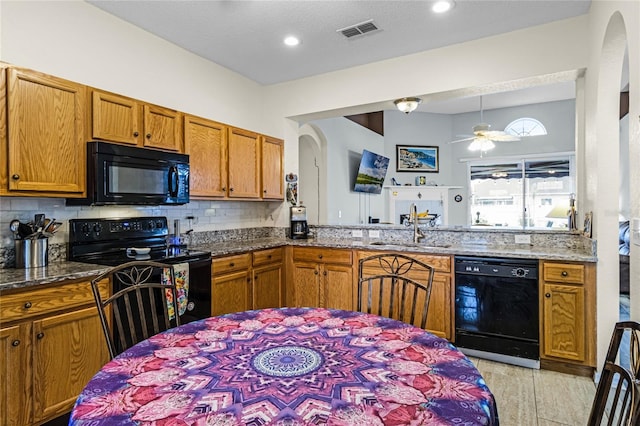 kitchen featuring black appliances, sink, ceiling fan, and light stone countertops