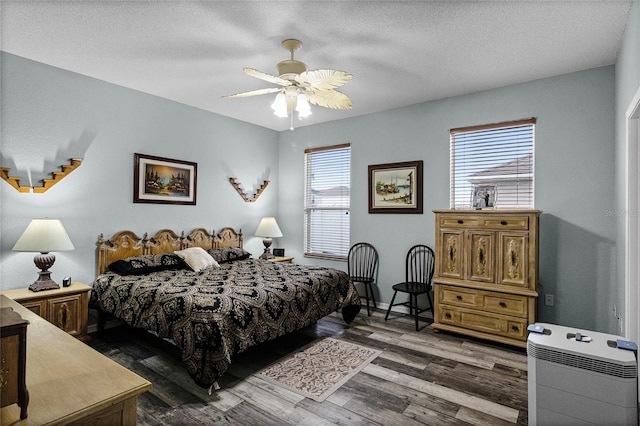 bedroom with dark hardwood / wood-style floors, ceiling fan, multiple windows, and a textured ceiling