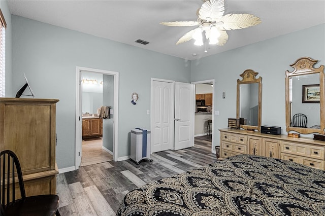 bedroom with dark wood-type flooring, ceiling fan, and connected bathroom