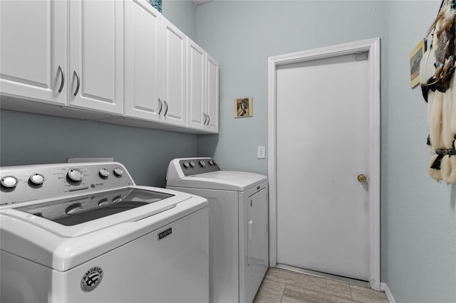 washroom featuring light tile patterned flooring, cabinets, and washer and dryer