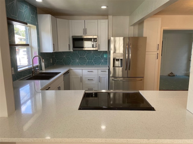 kitchen featuring white cabinets, sink, tasteful backsplash, light stone countertops, and appliances with stainless steel finishes