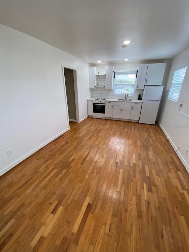 kitchen featuring decorative backsplash, sink, white cabinetry, light hardwood / wood-style flooring, and white appliances