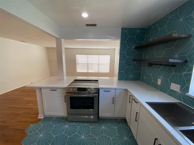 kitchen with sink, white cabinets, dark hardwood / wood-style flooring, backsplash, and stainless steel electric range