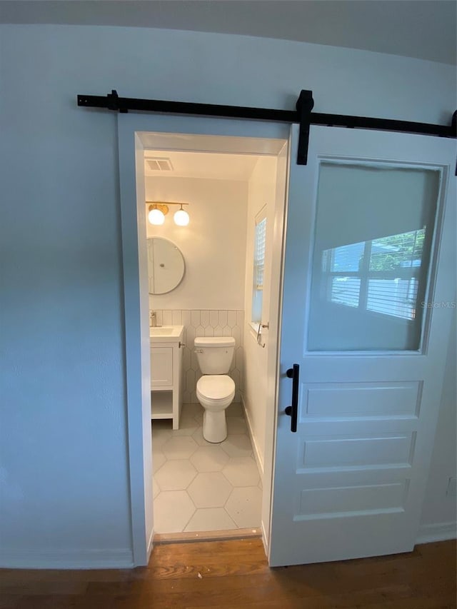 bathroom featuring hardwood / wood-style floors, vanity, tile walls, and toilet