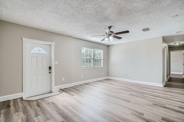 foyer entrance with light wood-type flooring, a textured ceiling, and ceiling fan