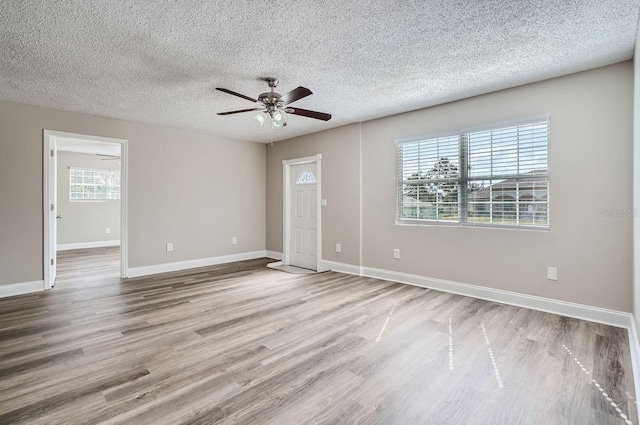 unfurnished room with a wealth of natural light, ceiling fan, a textured ceiling, and light hardwood / wood-style flooring