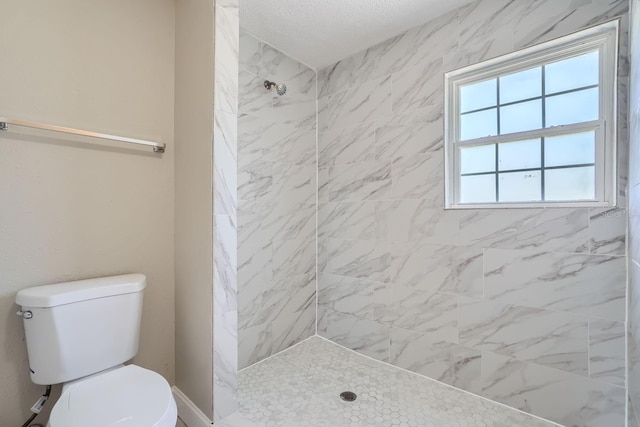 bathroom featuring a tile shower, a textured ceiling, and toilet