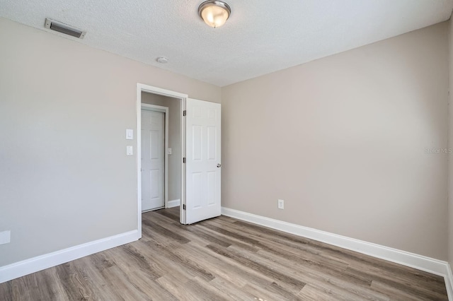 empty room featuring light hardwood / wood-style flooring and a textured ceiling