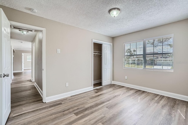 unfurnished bedroom featuring a closet, a textured ceiling, and light hardwood / wood-style flooring