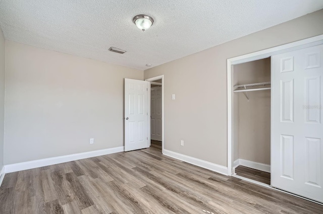 unfurnished bedroom with light hardwood / wood-style floors, a textured ceiling, and a closet