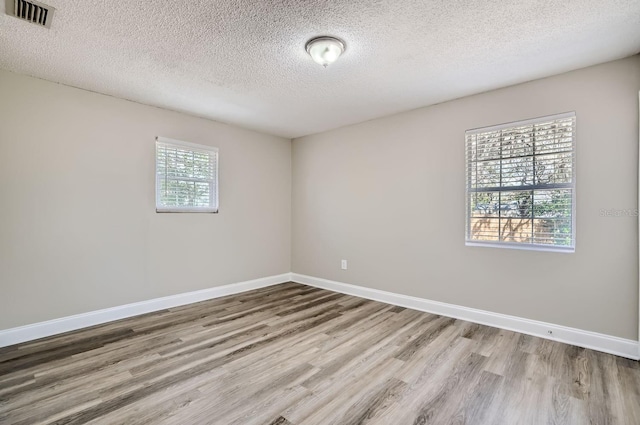 unfurnished room with wood-type flooring, a healthy amount of sunlight, and a textured ceiling