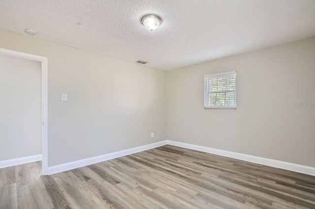 unfurnished room featuring wood-type flooring and a textured ceiling