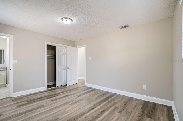 11335 Pickford St, Spring Hill, FL 34609 - unfurnished bedroom featuring light wood-style floors, a closet, a textured ceiling, and baseboards