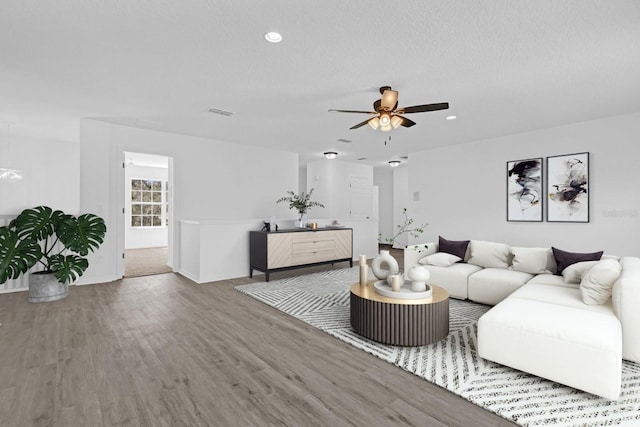 living room with hardwood / wood-style floors, a textured ceiling, and ceiling fan