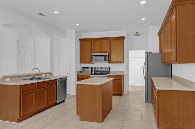 kitchen with sink, a kitchen island, stainless steel appliances, and light tile patterned floors