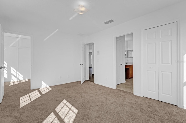 unfurnished bedroom featuring multiple closets and light colored carpet