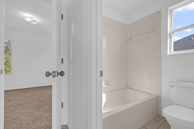 bathroom featuring tile patterned flooring, tiled shower / bath, and toilet