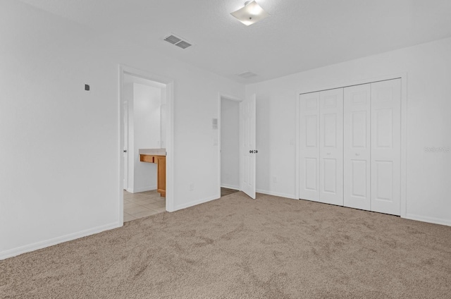 unfurnished bedroom featuring light carpet and a closet