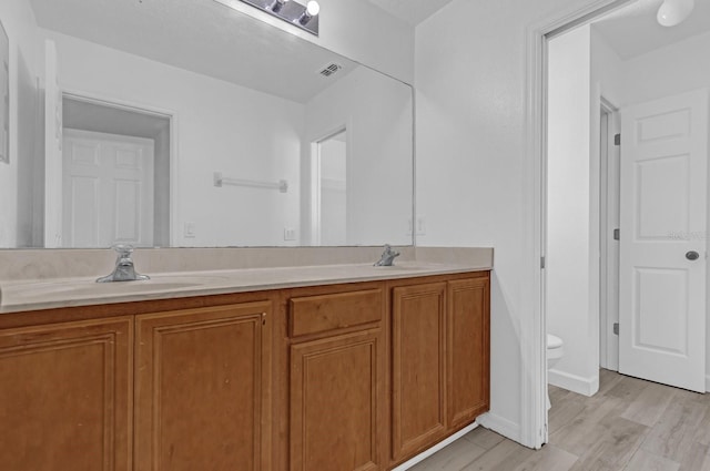 bathroom with wood-type flooring, vanity, and toilet