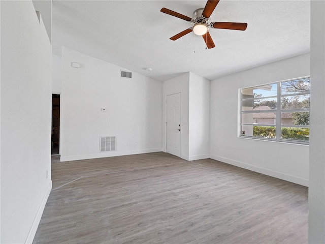 empty room featuring lofted ceiling, a textured ceiling, hardwood / wood-style flooring, and ceiling fan