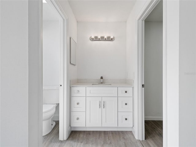 bathroom with toilet, vanity, and hardwood / wood-style floors