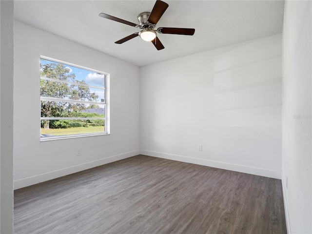 empty room featuring a textured ceiling, dark wood-type flooring, and ceiling fan