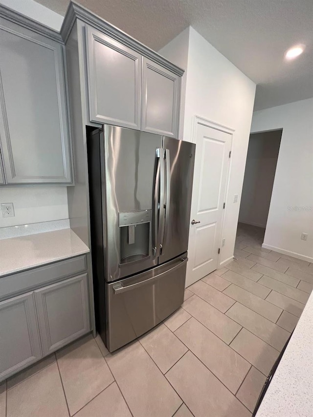 kitchen featuring gray cabinetry, light tile patterned floors, and stainless steel refrigerator with ice dispenser