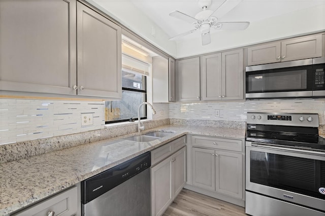 kitchen with gray cabinets, light stone countertops, sink, and appliances with stainless steel finishes