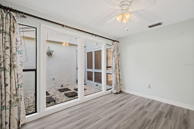 empty room featuring ceiling fan, a textured ceiling, and light wood-type flooring