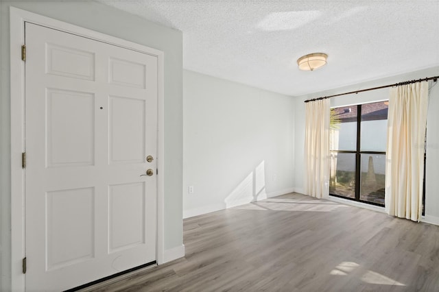 unfurnished room with light hardwood / wood-style flooring and a textured ceiling