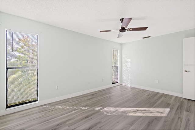 empty room with ceiling fan, a textured ceiling, and light wood-type flooring