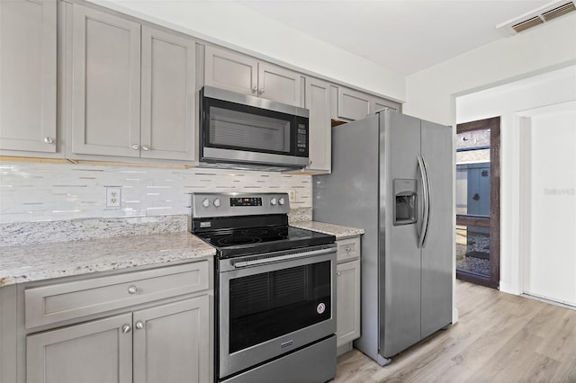 kitchen featuring decorative backsplash, gray cabinets, and stainless steel appliances