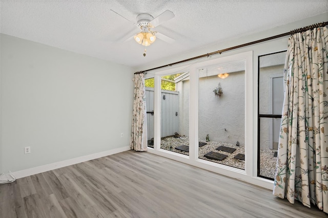 unfurnished room with a textured ceiling, light hardwood / wood-style floors, and ceiling fan