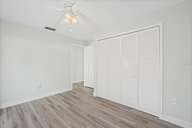 unfurnished bedroom with a textured ceiling, a closet, ceiling fan, and light hardwood / wood-style floors