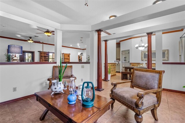 sitting room with light tile patterned floors, ceiling fan with notable chandelier, ornate columns, and crown molding