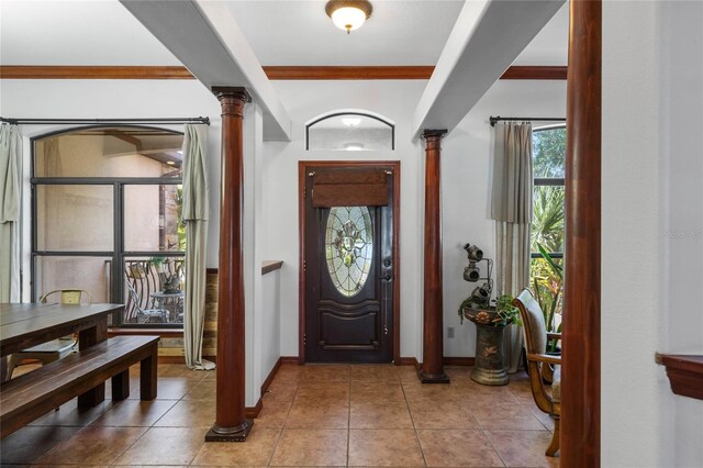 foyer with tile patterned flooring, ornate columns, and crown molding