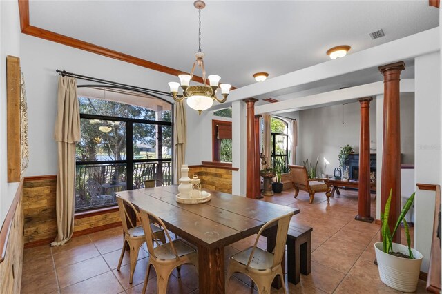 tiled dining area featuring an inviting chandelier, crown molding, and decorative columns