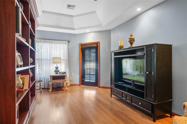 interior space with light hardwood / wood-style floors and a raised ceiling