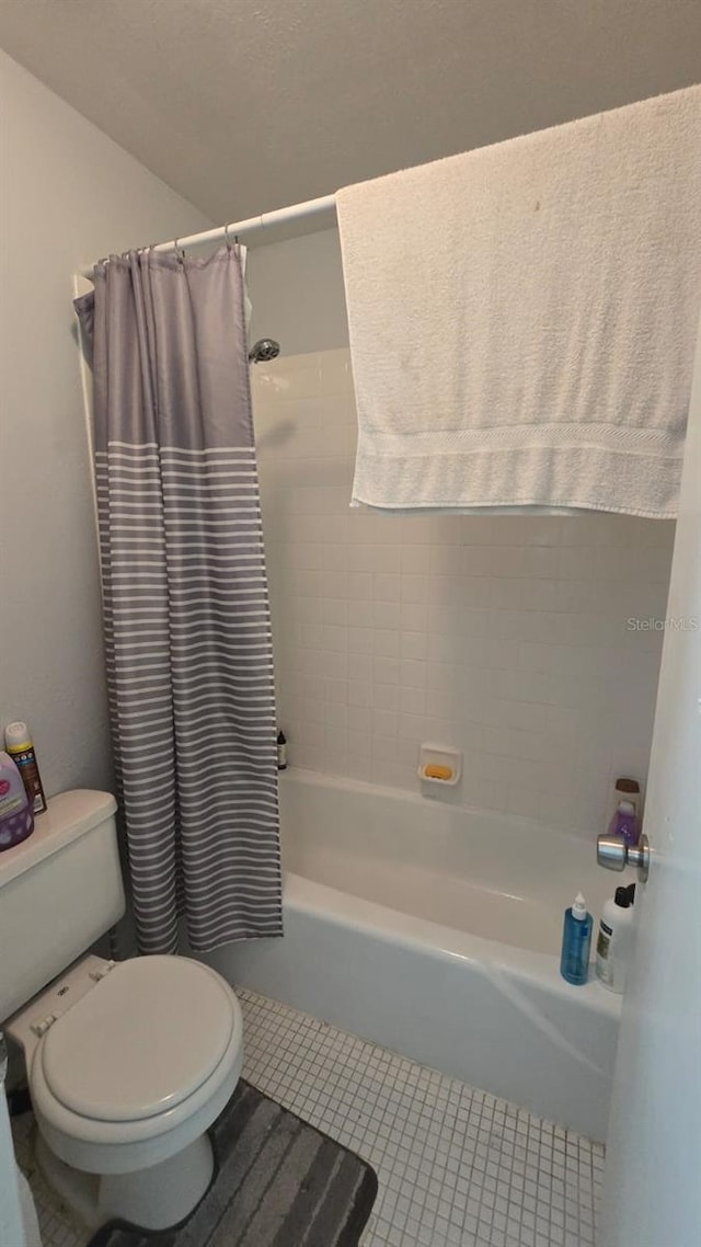 bathroom featuring tile patterned flooring, toilet, and shower / tub combo with curtain