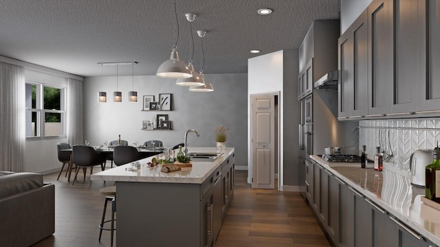 kitchen featuring a textured ceiling, dark hardwood / wood-style flooring, hanging light fixtures, sink, and wall chimney exhaust hood