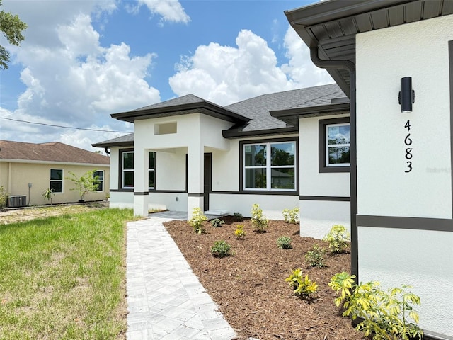 4683 Boston Ter, North Port, FL 34288 - view of front of house featuring stucco siding, cooling unit, roof with shingles, and a front lawn