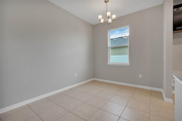 spare room with a notable chandelier and light tile patterned flooring