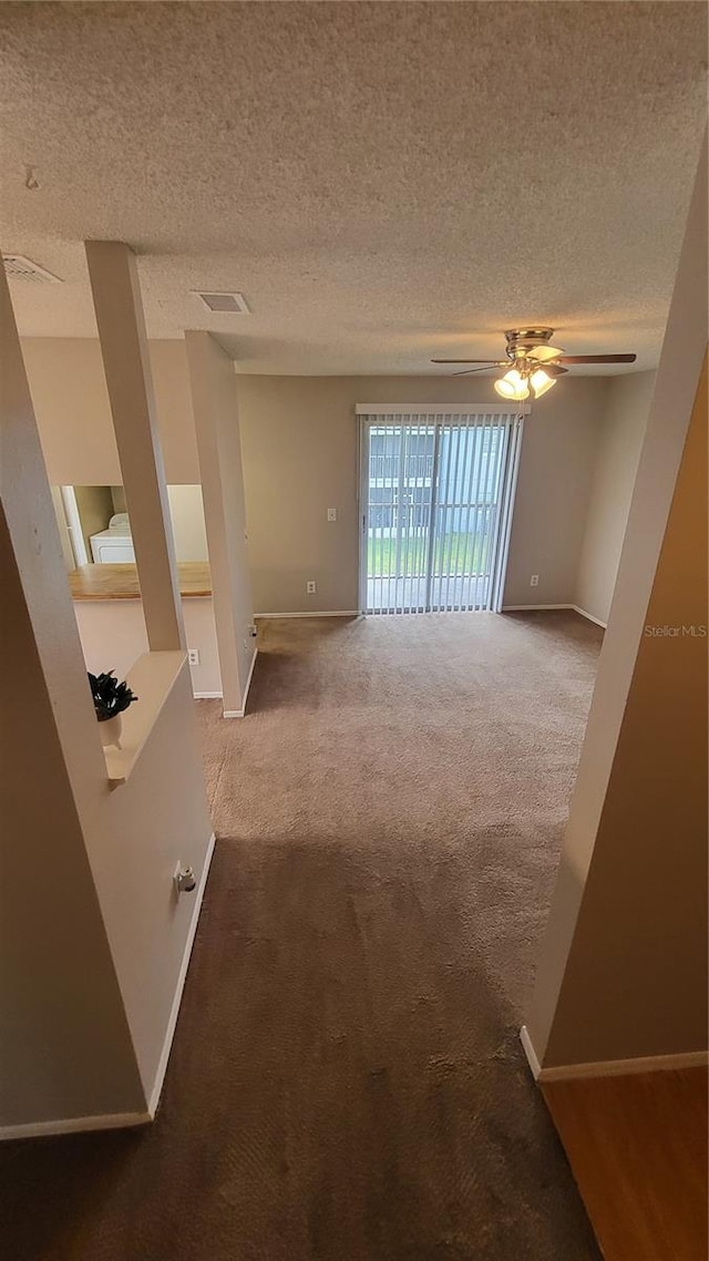 spare room with a textured ceiling, carpet floors, and ceiling fan