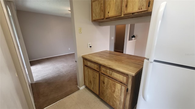 kitchen featuring light carpet and white fridge