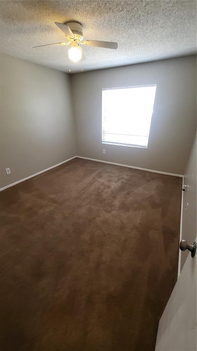 carpeted empty room featuring ceiling fan and a textured ceiling