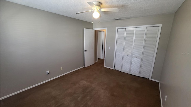 unfurnished bedroom featuring ceiling fan, a textured ceiling, a closet, and dark carpet