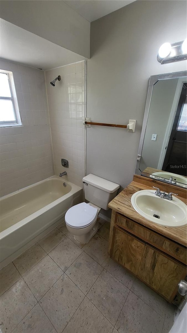 full bathroom featuring tiled shower / bath, tile patterned floors, toilet, and vanity