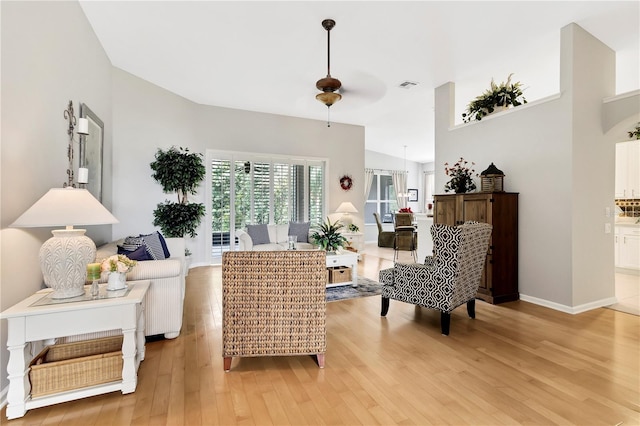 living room featuring ceiling fan, light hardwood / wood-style floors, and lofted ceiling